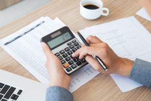 comment reduire ses impots avec l'immobilier-homme qui tient une calculatrice dans ses mains